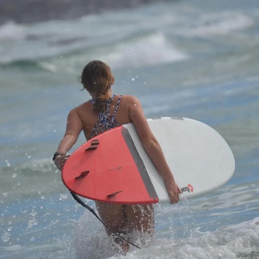 Surfer walking into the sea with a board